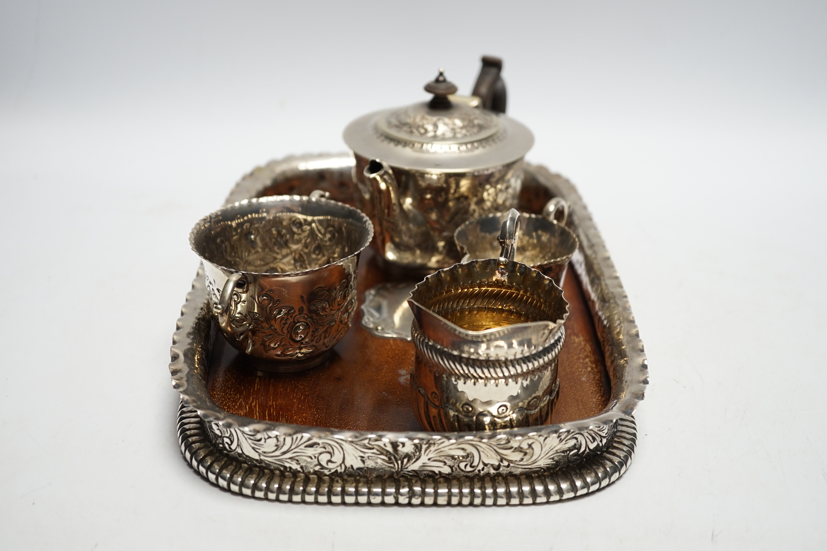 A matched Victorian repousse silver four piece bachelor's tea set, gross 12.8oz and silver plated? mounted wooden tea tray.